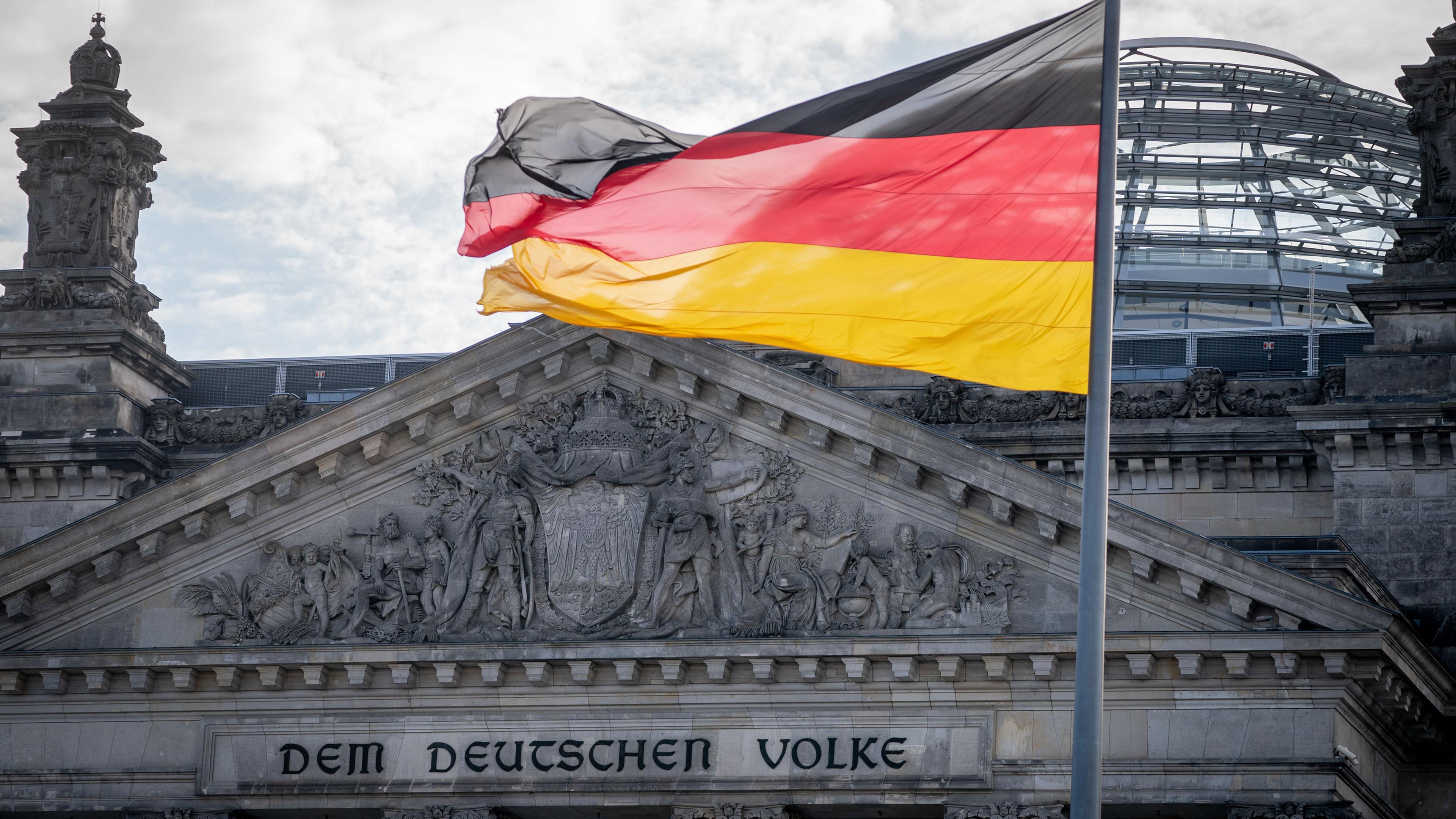 Die Sonne steht am Morgen hinter dem Reichstagsgebäude mit dem Bundestag. 