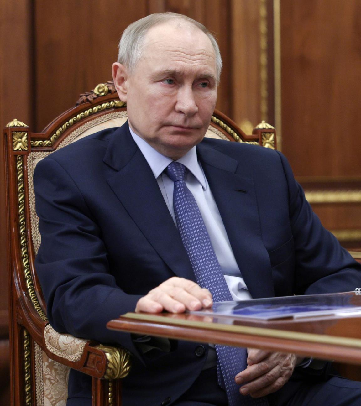 Putin sitzend und zuhörend im Anzug