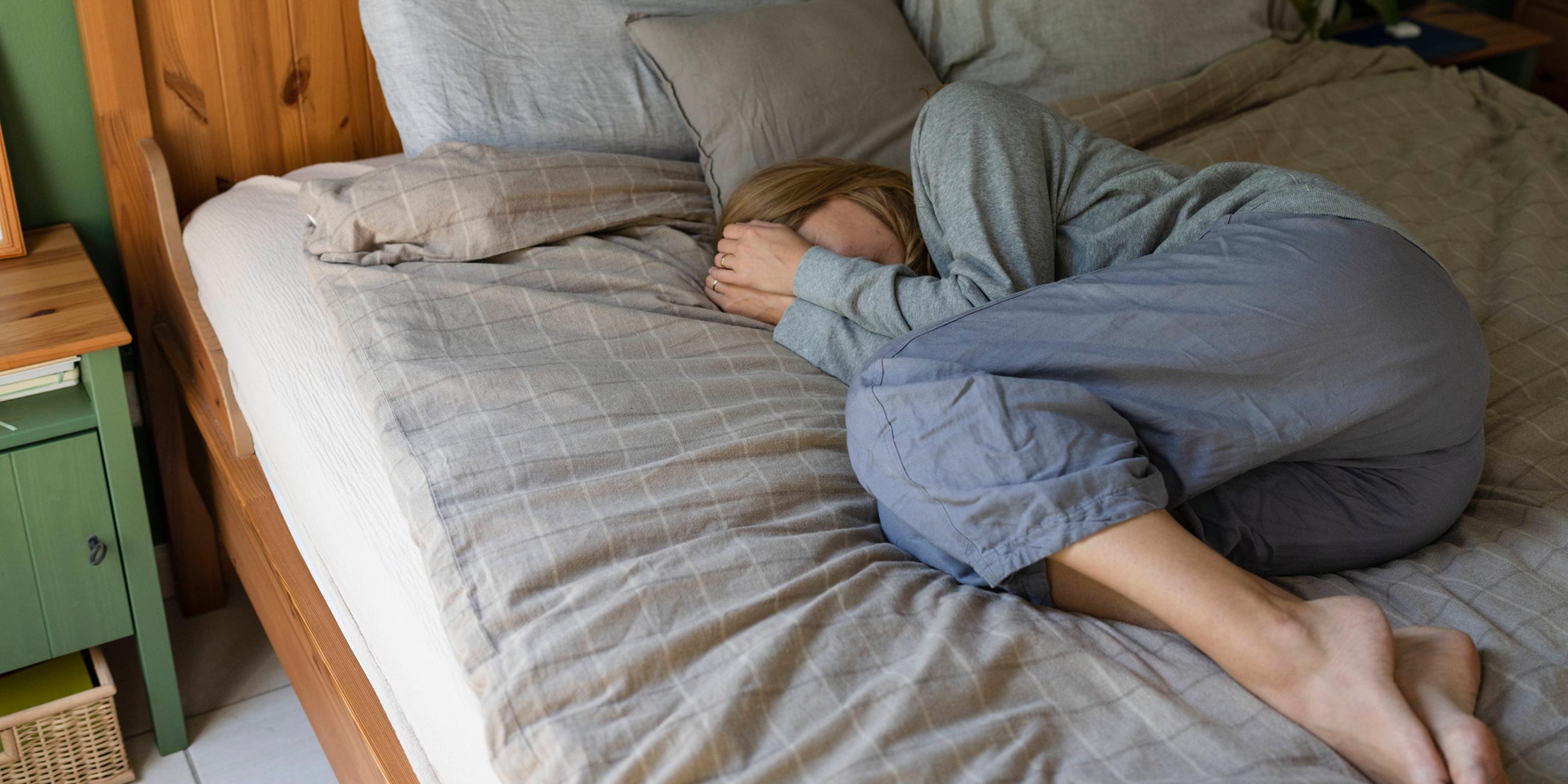 Gestresste Frau liegt zu Hause im Bett
