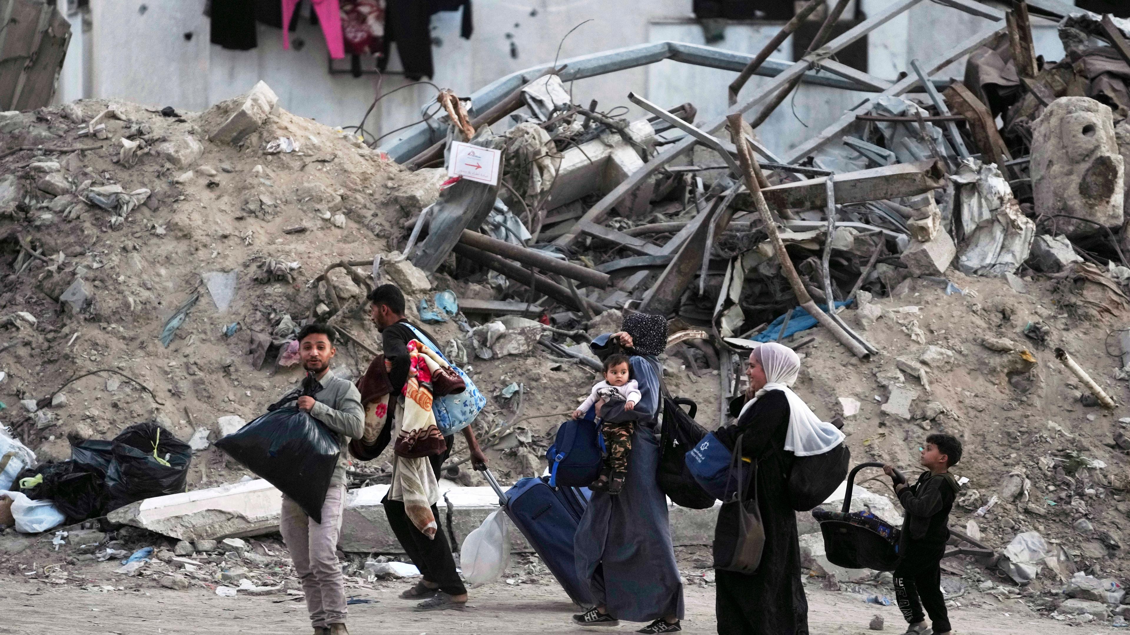 Menschen in Gaza verlassen ihre Häuser in einer zerstörten Nachbarschaft.