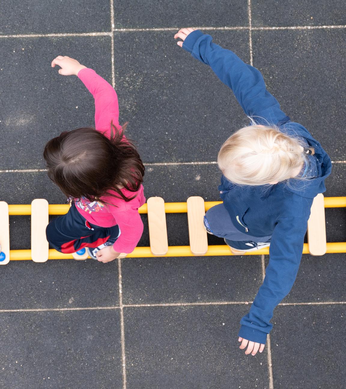 Drei Kinder balancieren auf einem Spielplatz
