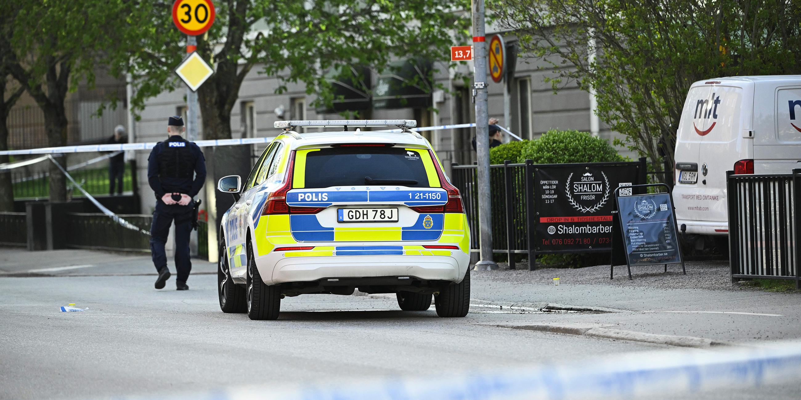Einsatzfahrzeug und ein Polizist stehen am Einsatzort nach Schüssen am Vaksala-Platz im Zentrum von Uppsala, Schweden